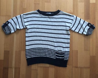 May include: A striped sweater with a navy blue and white colour scheme. The sweater has a small pocket on the front and a crew neck.