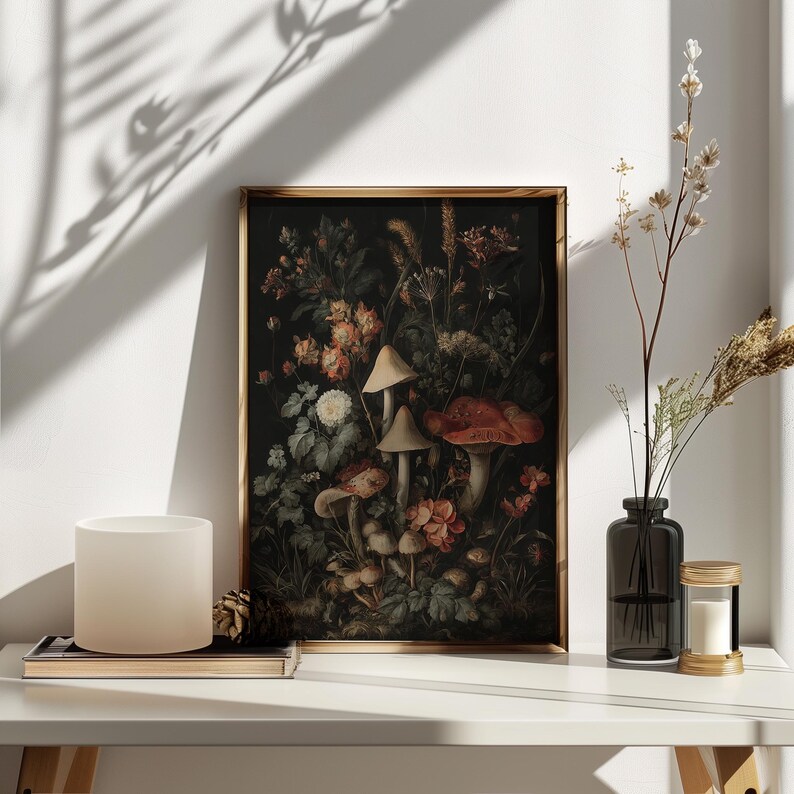 May include: A framed botanical print with a dark backdrop, showcasing mushrooms and flowers in red, orange, and white hues. The artwork is in a gold frame, displayed on a white surface.