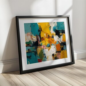 May include: An abstract painting in a black frame. The artwork features bold brushstrokes of teal, yellow, white, orange, and black. The painting is leaning against a white wall on a wooden floor, creating a modern art display.