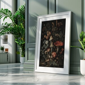May include: A framed art print with a detailed botanical illustration of mushrooms and flowers in shades of red, brown, and cream. The white framed artwork leans against a green wall, with potted plants in the foreground.
