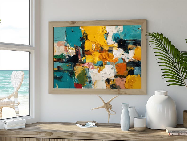 May include: Abstract art painting in a light wood frame. The artwork features bold brushstrokes of yellow, teal, white, orange, and pink. The painting is displayed on a wooden surface with decorative items.