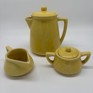 5 piece yellow vintage McCoy pottery set. Teapot with lid, sugar bowl with lid, and creamer. Small chip in sugar bowl as shown in photos.