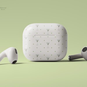 May include: White wireless charging case with a repeating pattern of martini glasses and gold dots. The case is for Apple AirPods.