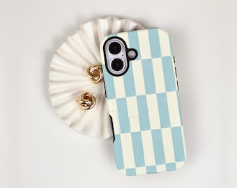 May include: A light blue and white checkered phone case with a black camera lens. Two gold-colored knot earrings and a white, scalloped dish are also in the image.