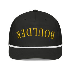Puede incluir: Gorra de béisbol negra con ribete de cuerda blanca y la palabra "BOULDER" bordada en amarillo en la parte delantera.