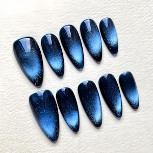 Puede incluir: Diez u&ntilde;as postizas de ojo de gato azul y plateado en forma de stiletto.