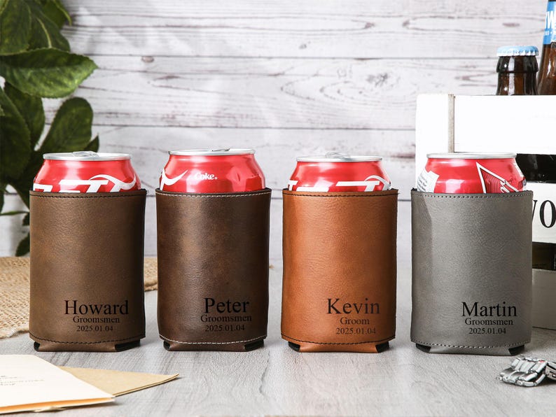 May include: Four personalized can coolers in brown, dark brown, tan, and gray, each holding a red soda can. The coolers are engraved with names and the text "Groomsmen" or "Groom" and the date 2025.01.04.