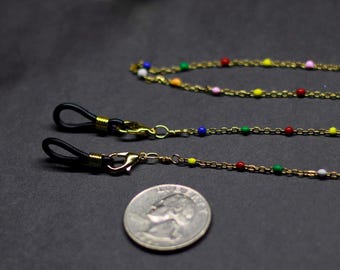 Puede incluir: Cadenas para gafas con cuentas de colores y cadena y cierres de metal dorado. Las cadenas tienen bucles de goma negra para sujetar a las gafas. Se incluye una moneda como referencia de tamaño.