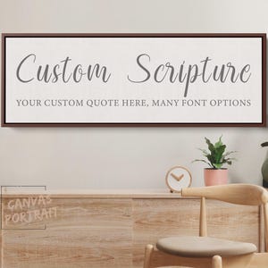 May include: A rectangular canvas print with a brown frame displays the words "Custom Scripture" in elegant gray script. Below, it reads "YOUR CUSTOM QUOTE HERE, MANY FONT OPTIONS". The canvas hangs above a wooden cabinet.