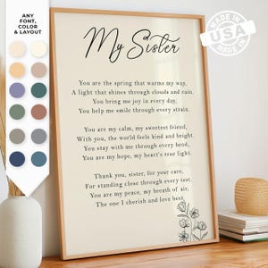 May include: Framed print with the words "My Sister" in elegant script. The print features a poem about sisterhood, with floral accents in the corner. The frame is a light wood color, and the background is a soft cream.