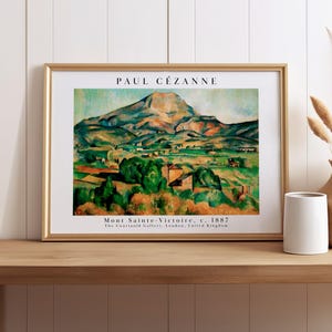May include: A framed art print of Paul Cézanne's Mont Sainte-Victoire, c. 1887. The painting features a mountain landscape with green, blue, and orange tones. The text reads PAUL CÉZANNE, Mont Sainte-Victoire, c. 1887, The Courtauld Gallery, London, United Kingdom.