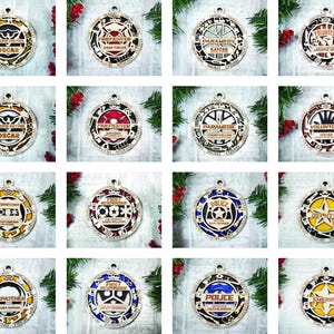 Könnte beinhalten: Zwölf runde Holzornamente mit verschiedenen Designs und Texten. Die Ornamente zeigen eine Vielzahl von Berufen, darunter Polizei, Feuerwehr, Sheriff, Sanitäter und Freiwillige. Jedes Ornament hat einen anderen Namen und Titel.