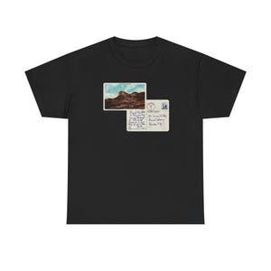 Peut inclure: T-shirt noir avec un motif de carte postale vintage. La carte postale représente un paysage de montagne et du texte. Le t-shirt est fait d'une matière douce, adaptée au port quotidien.