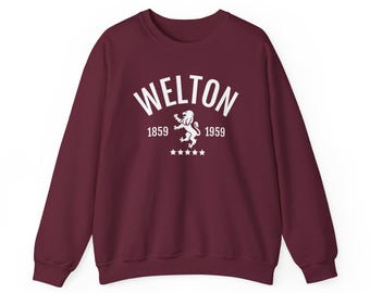 May include: A maroon sweatshirt with the word "WELTON" in white arched lettering. Below the word are the numbers "1859" and "1959" flanking a white lion emblem. Five white stars are below the emblem.