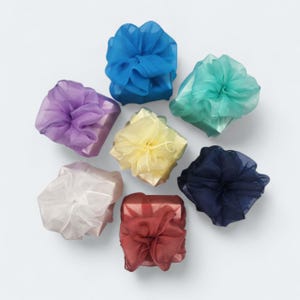 May include: Seven square gift boxes wrapped in solid colored paper, each topped with a large, voluminous bow made of sheer, translucent organza ribbon. The colors include blue, teal, purple, yellow, white, dark navy, and deep red.