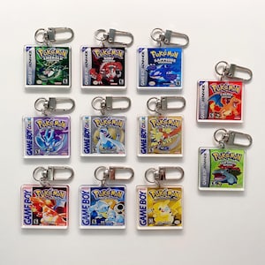 Puede incluir: Un conjunto de diez llaveros con diferentes cartuchos de juegos de Pokémon. Cada llavero está hecho de acrílico transparente y presenta una portada de juego de Pokémon diferente. Los llaveros están todos unidos a llaveros de plata.