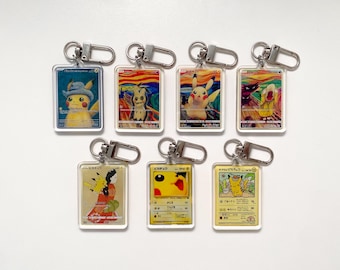 Op de afbeelding: Een verzameling van zeven rechthoekige sleutelhangers met verschillende Pikachu-ontwerpen. Elke sleutelhanger heeft een zilverkleurige sluiting. De ontwerpen tonen Pikachu in verschillende artistieke stijlen, met heldere kleuren en gedetailleerde illustraties.