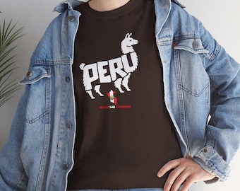 Puede incluir: Camiseta marrón con un gráfico blanco de una llama y la palabra "PERU". Debajo, una pequeña bandera peruana y el texto "VISION LAB CREATIONS". La persona lleva una chaqueta vaquera. El diseño celebra Perú.