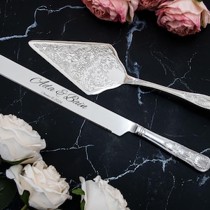 Puede incluir: Un juego de cuchillo y servidor para pastel de plata con un diseño floral grabado. El cuchillo está grabado con el texto "Ada & Bain, December 8, 2024".