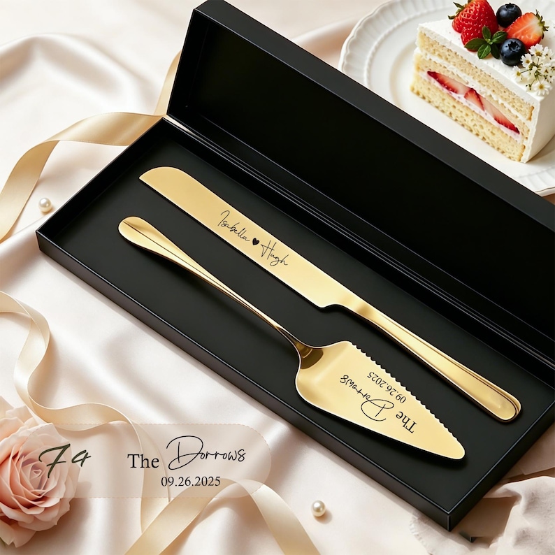 Puede incluir: Un juego de cuchillo y pala para pastel en tono dorado dentro de una caja de presentaci&oacute;n rectangular negra. El cuchillo est&aacute; grabado con Isabella y Hugh, mientras que la pala presenta el texto The Darrows y la fecha 09.26.2025 en cursiva.