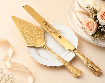 Puede incluir: Un juego de cuchillo y pala para pastel en tono dorado con grabados florales ornamentales en el mango y la hoja. La hoja del cuchillo está grabada con el texto CAREY & SLATER y la fecha 09. 06. 2025, junto a un pequeño motivo de hoja decorativo.