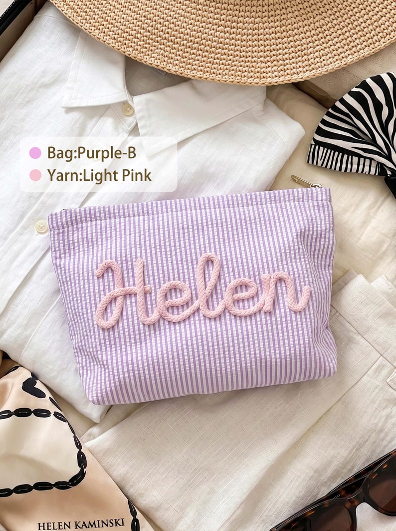 May include: A rectangular purple and white seersucker zippered pouch featuring the name Helen in raised light pink yarn lettering. The text on the overlay reads Bag:Purple-B and Yarn:Light Pink. The pouch is positioned on a white shirt.