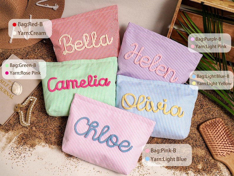 May include: Five rectangular zippered pouches with vertical stripes in red, green, purple, light blue, and pink. Each pouch features a name embroidered in raised yarn: Bella in cream, Camelia in rose pink, Helen in light pink, Olivia in yellow, and Chloe in light blue.