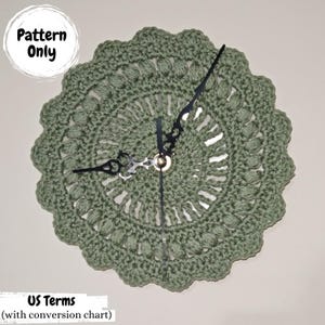 May include: A sage green, crocheted clock with black clock hands. The clock face has a circular, scalloped edge and a detailed, openwork design. Text on the image reads "Pattern Only" and "US Terms (with conversion chart)".