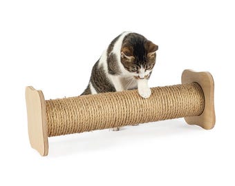 May include: A brown and white cat scratching a sisal-covered scratching post. The scratching post is made of wood and has a cylindrical shape. The cat is standing on the post and is using its claws to scratch the sisal.