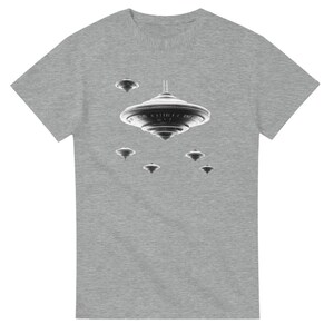 Könnte beinhalten: Graues T-Shirt mit einer schwarz-weißen Grafik von mehreren fliegenden Untertassen. Das Design zeigt eine große zentrale UFO mit kleineren darum herum, wodurch ein Weltraum-Thema entsteht.
