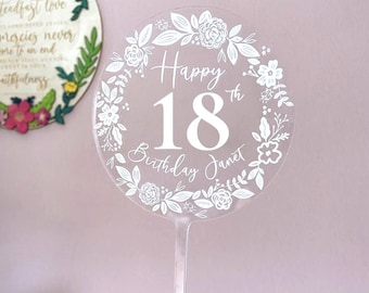 Könnte beinhalten: Klare Acryl-Tortenaufsatz mit weißem Blumenmuster und dem Text "Happy 18th Birthday Janet".