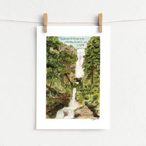 May include: A watercolour print featuring a cascading waterfall surrounded by dense green trees and rocky terrain. The text at the top reads, "Mightier than the thunder of the great waters, the Lord on high is mighty." The artwork is displayed on a white paper.