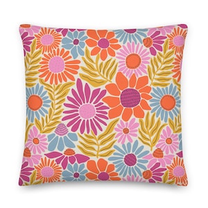 May include: A throw pillow with a floral pattern featuring pink, orange, and blue flowers on a cream background.