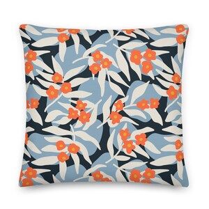 May include: A throw pillow with a floral pattern featuring orange flowers and white leaves on a blue and white background.