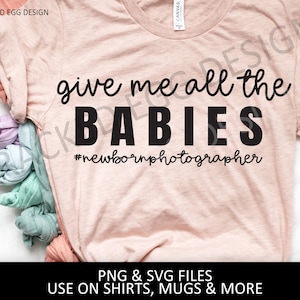 May include: A pink t-shirt with the text "give me all the BABIES #newbornphotographer" in black.