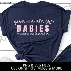 May include: A navy blue t-shirt with the text "give me all the BABIES #newbornphotographer" in pink lettering.