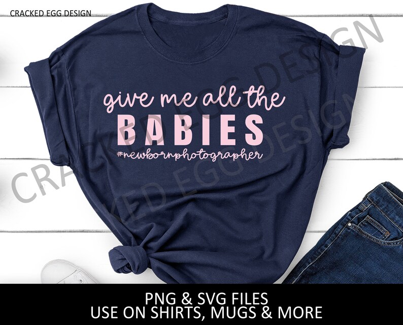 May include: A navy blue t-shirt with the text "give me all the BABIES #newbornphotographer" in pink lettering.