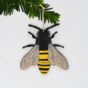 Peut inclure: Une décoration d'abeille en bois avec des rayures noires et jaunes, des ailes grises et une ficelle pour l'accrocher.