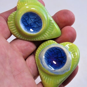May include: Two green heart-shaped ceramic trinket dishes with blue and white glazed interiors.