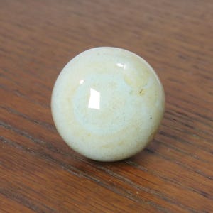 May include: A light blue ceramic knob with a white swirl pattern.