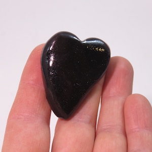 May include: A heart-shaped black obsidian stone with a shiny, polished surface.