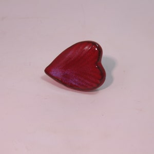 May include: A red heart-shaped ceramic ornament with a textured surface.