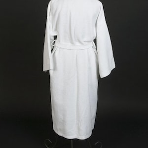 May include: A white bathrobe with a shawl collar and a tie belt. The robe is made of a soft, absorbent material and is perfect for lounging around the house.