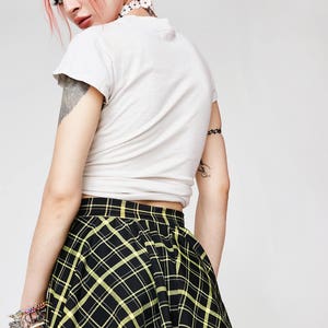 May include: A black and yellow plaid mini skirt with a flared silhouette. The skirt is made of a soft, stretchy fabric and has a comfortable fit.