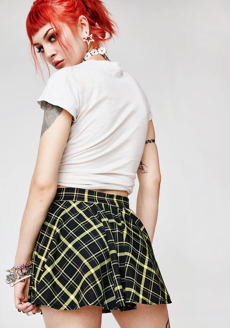 May include: A black and yellow plaid mini skirt with a flared silhouette. The skirt is made of a soft, stretchy fabric and has a comfortable fit.