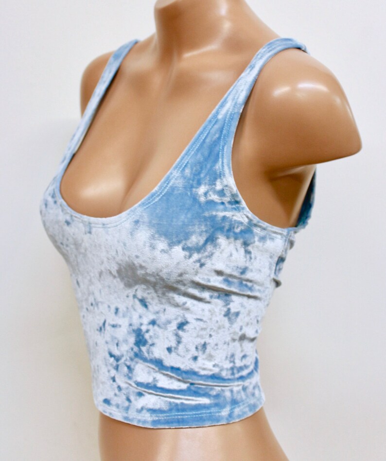 May include: A light blue cropped tank top made of crushed velvet. The tank top has a scoop neck and thin straps.