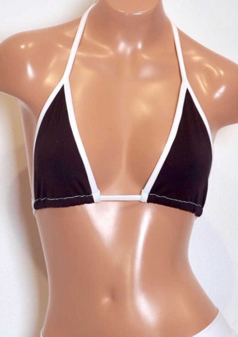 May include: A black triangle bikini top with white trim. The top has adjustable straps and a halter neck style.