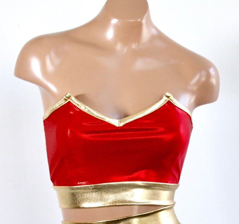 May include: Red strapless top with gold trim. The top has a sweetheart neckline and a gold band around the bottom.