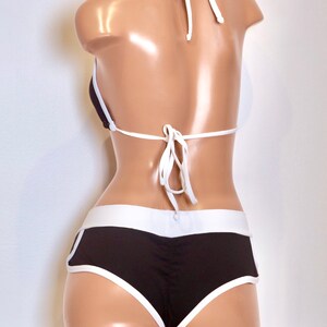 May include: Black and white bikini with a halter top and high-waisted bottoms. The bikini has a white trim around the edges.