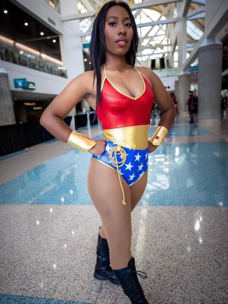 May include: A woman dressed as Wonder Woman in a red, gold and blue costume with a star-spangled design. She is wearing black boots and a gold headband.